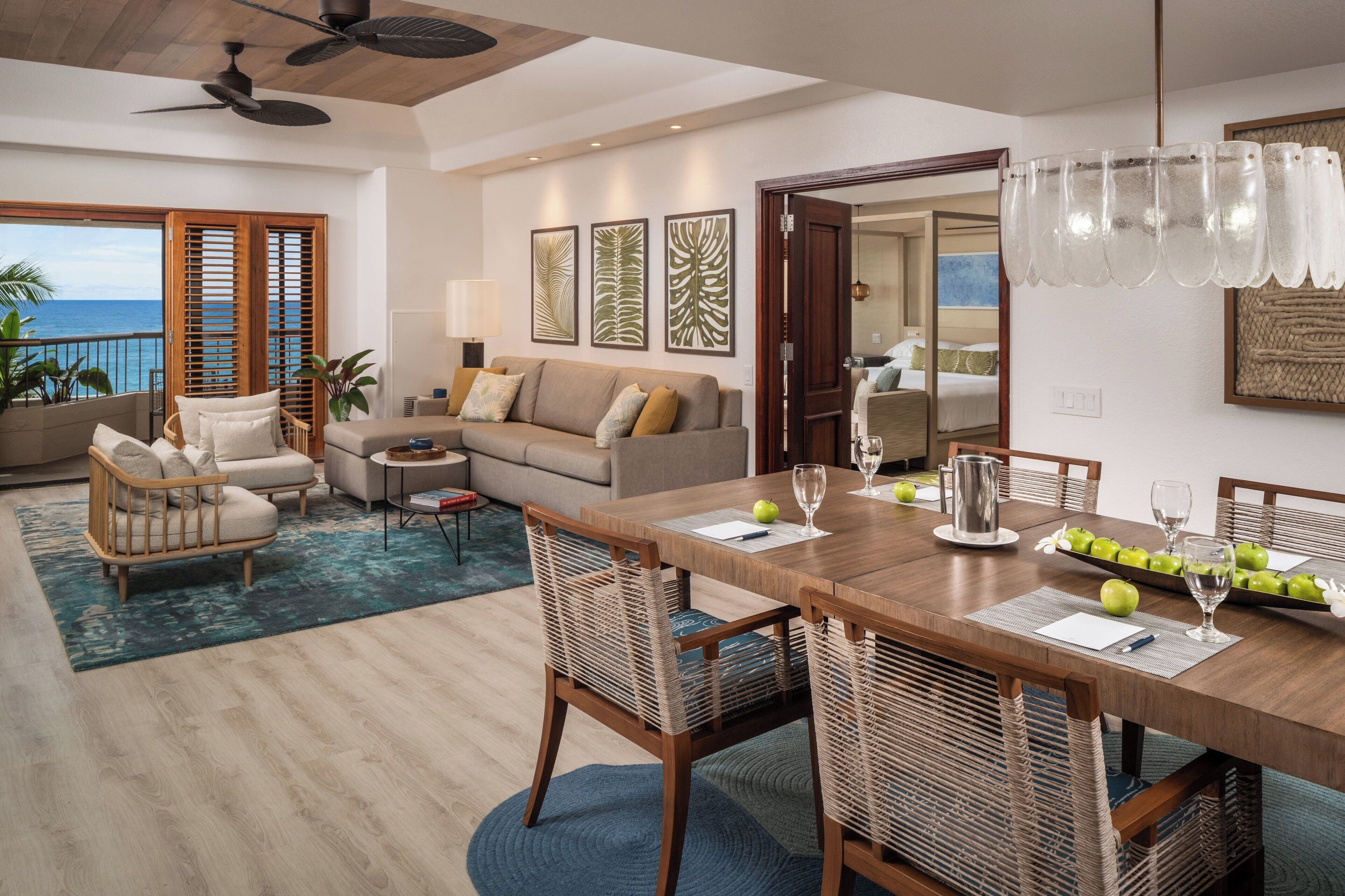 Un salón amplio con una mesa de comedor de madera, sillas de mimbre y vistas al océano.