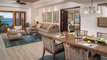 Un salón amplio con una mesa de comedor de madera, sillas de mimbre y vistas al océano.