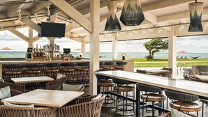 A beachside bar with wicker furniture, a long counter, and a view of the ocean. - Sheraton Kauai Coconut Beach Resort (Kapaa)