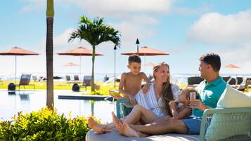 Eine Familie am Pool mit Sonnenschirmen und Liegestühlen.