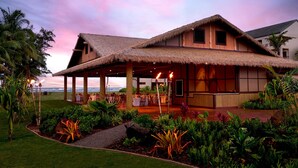 A resort with a thatched-roof structure, outdoor seating, and tropical landscaping. - Sheraton Kauai Coconut Beach Resort (Kapaa)