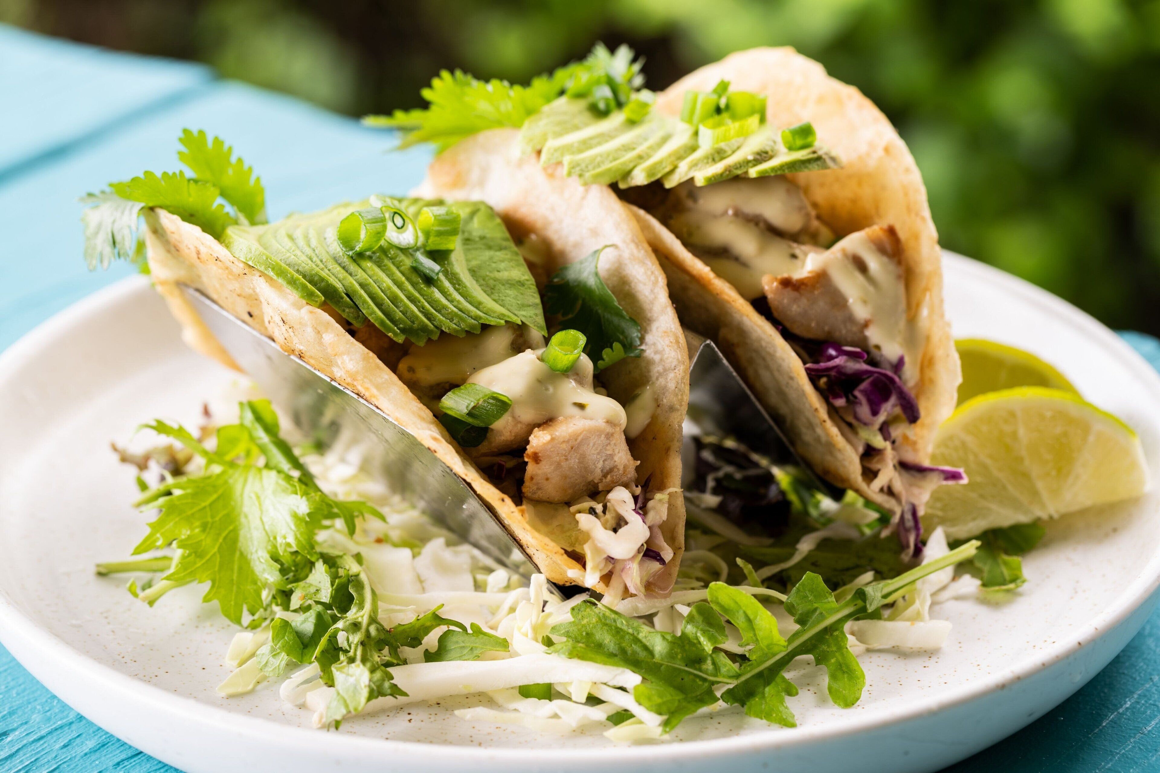 A plate of tacos with lettuce and a lime wedge.