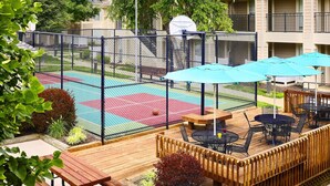Pátio com quadra de basquete, área de estar externa e espaço cercado para brincar.