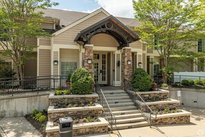 A building with a stone facade, a central entrance with a covered porch, and steps leading up to the entrance. - AVIA Residences on Lincoln- Extended Stay (Malvern)