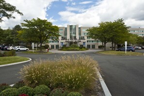 A hotel with a central entrance, landscaped gardens, and a parking area. - Embassy Suites by Hilton Parsippany (Parsippany)