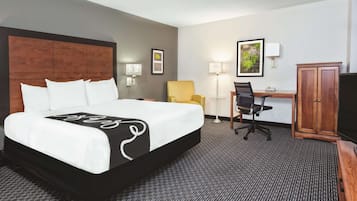 Une chambre d’hôtel avec un grand lit, un bureau avec une chaise, une lampe et une armoire.