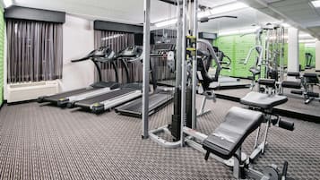 Un gimnasio con cintas de correr, una banca para pesas y diversas máquinas de ejercicio.