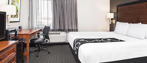 Une chambre d’hôtel équipée d’un lit, d’un bureau, d’une chaise et d’un téléviseur.