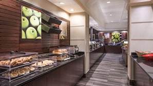 A buffet area with various food items, a wooden wall with a poster, and a tiled floor.