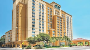 A multi-story hotel with a prominent sign, a covered outdoor area, and a well-maintained landscape.