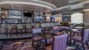 A hotel lobby with a bar area, seating arrangements, and a patterned carpet.