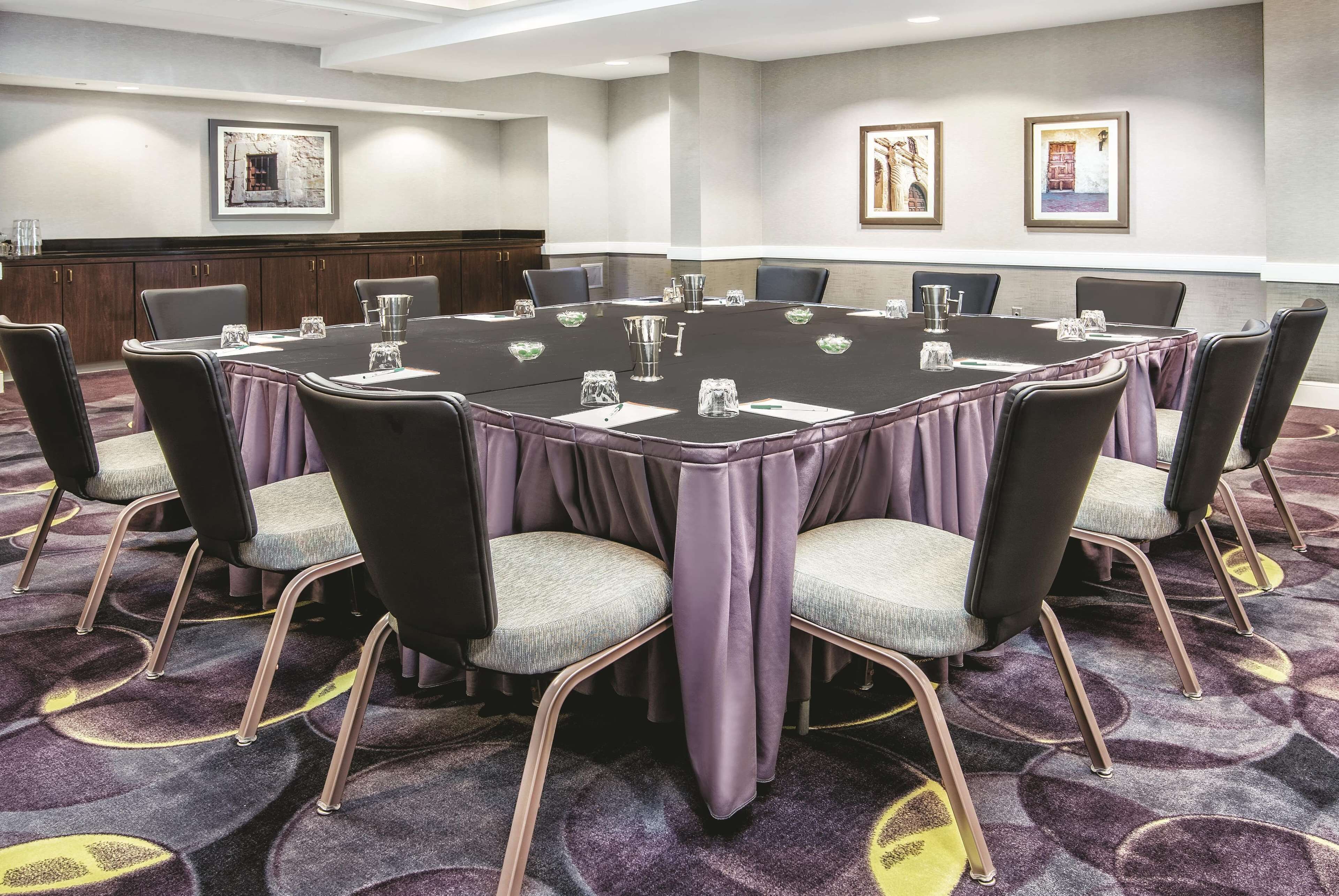 A conference room with a round table, chairs, and a carpeted floor.