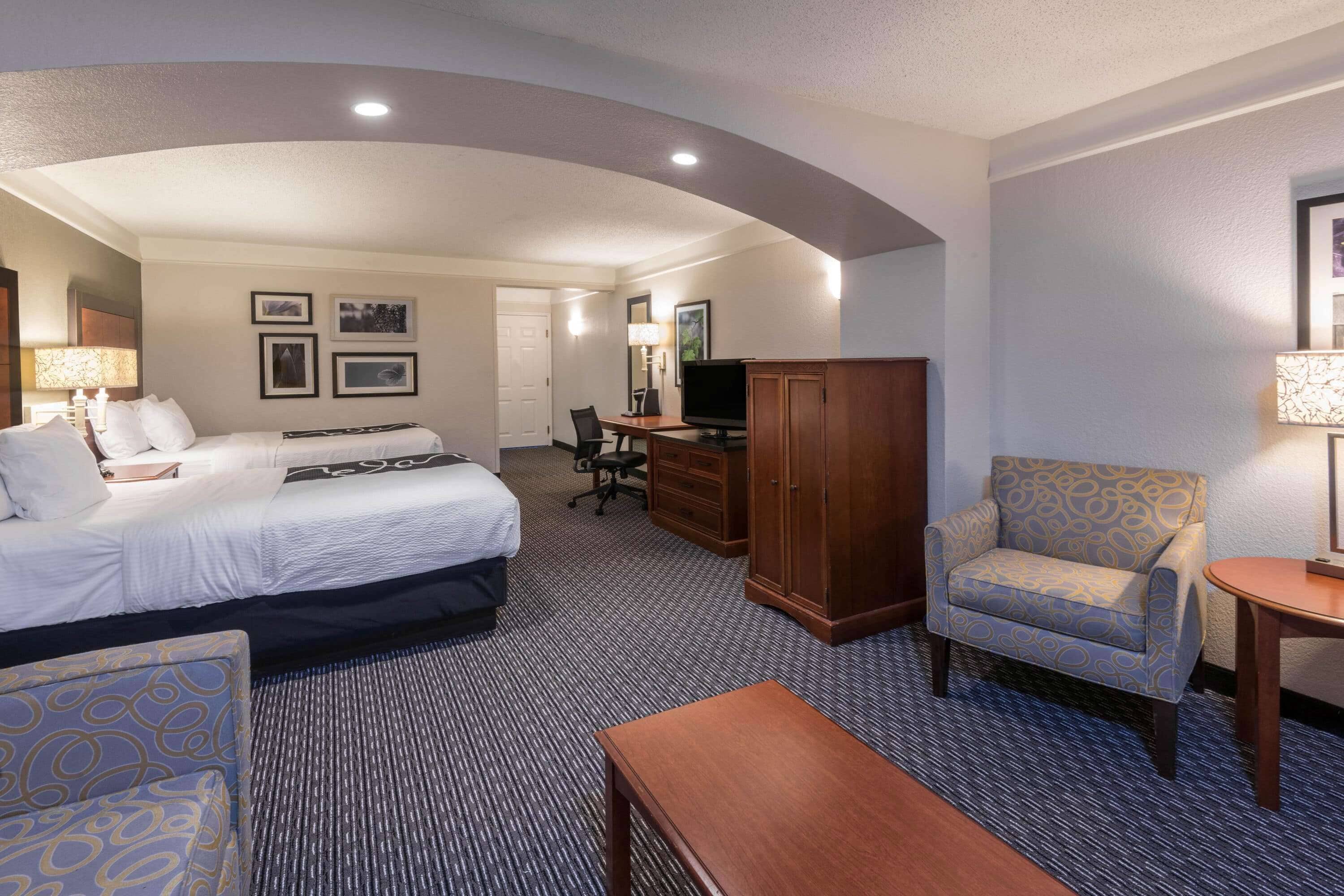 A hotel room with a bed, a desk, a chair, a TV, and a wardrobe.