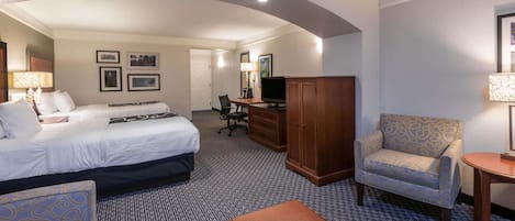 Una habitación de hotel con cama, escritorio, silla, televisor y armario.