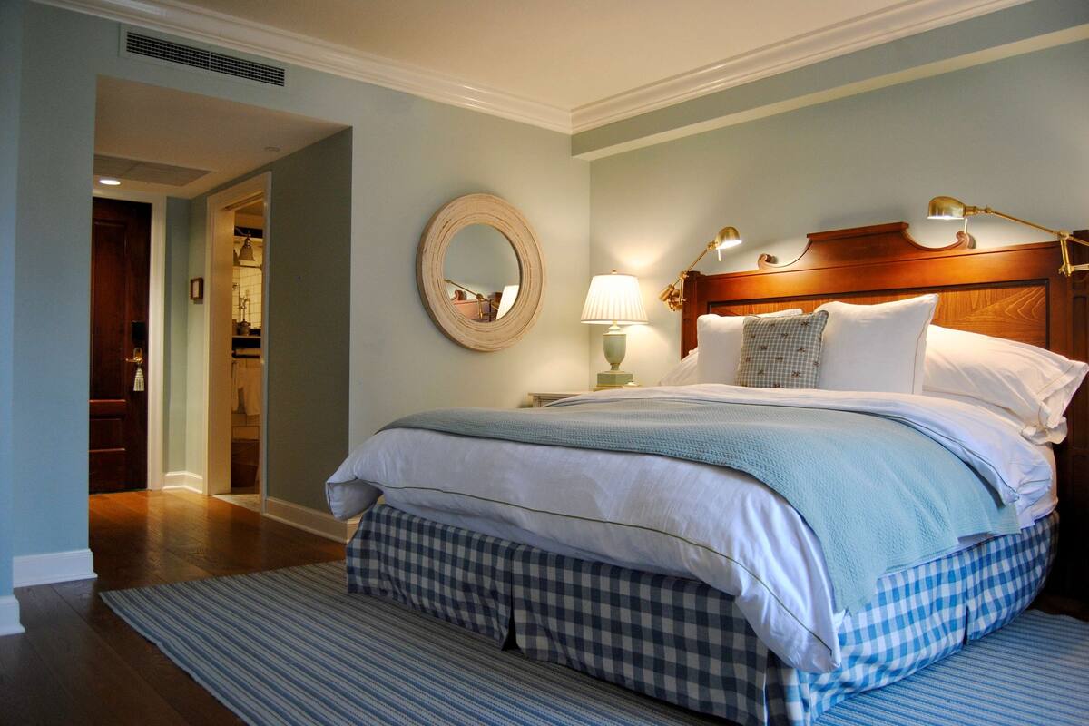 A neatly made bed with a blue and white checkered bedspread, a wooden headboard, and two bedside lamps.