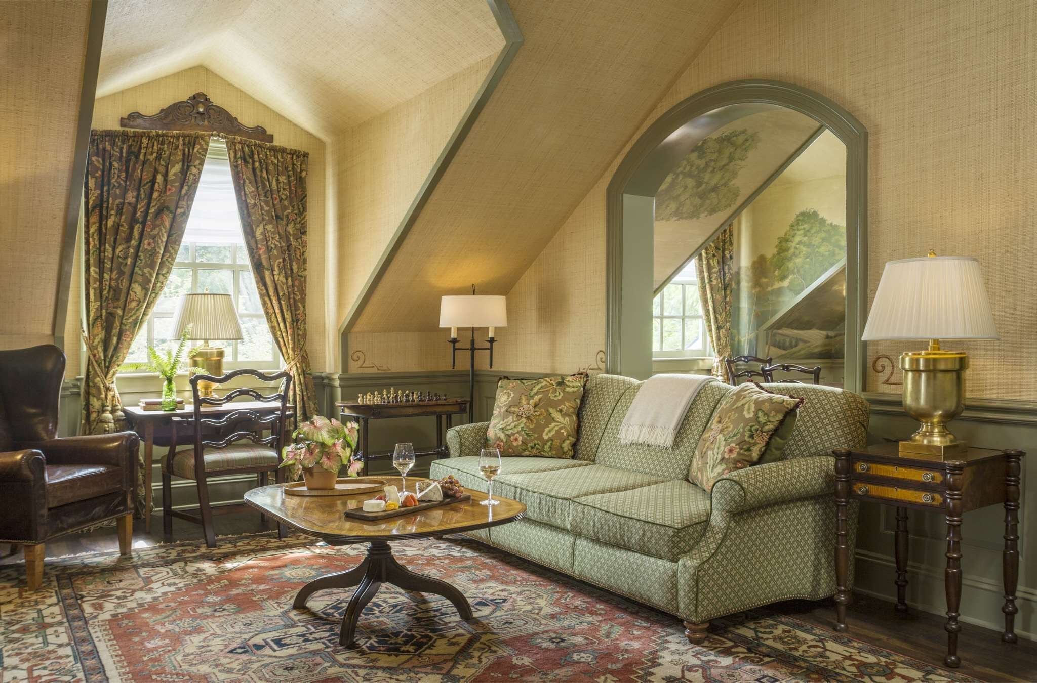 A traditional room with a green patterned sofa, a wooden coffee table, a mirror, and a lamp.