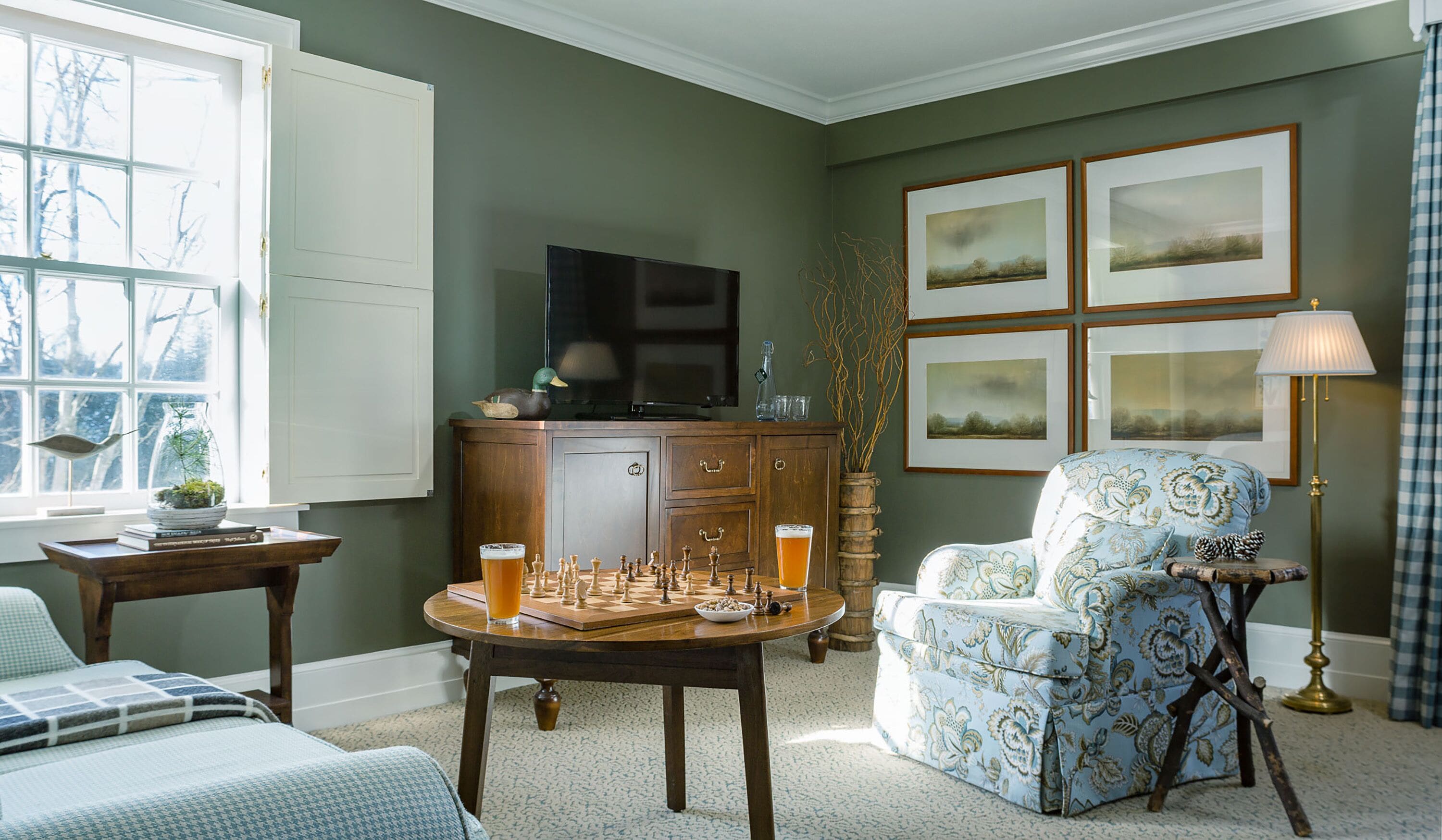 A cozy living room with a chessboard, a television, and framed pictures on the wall.
