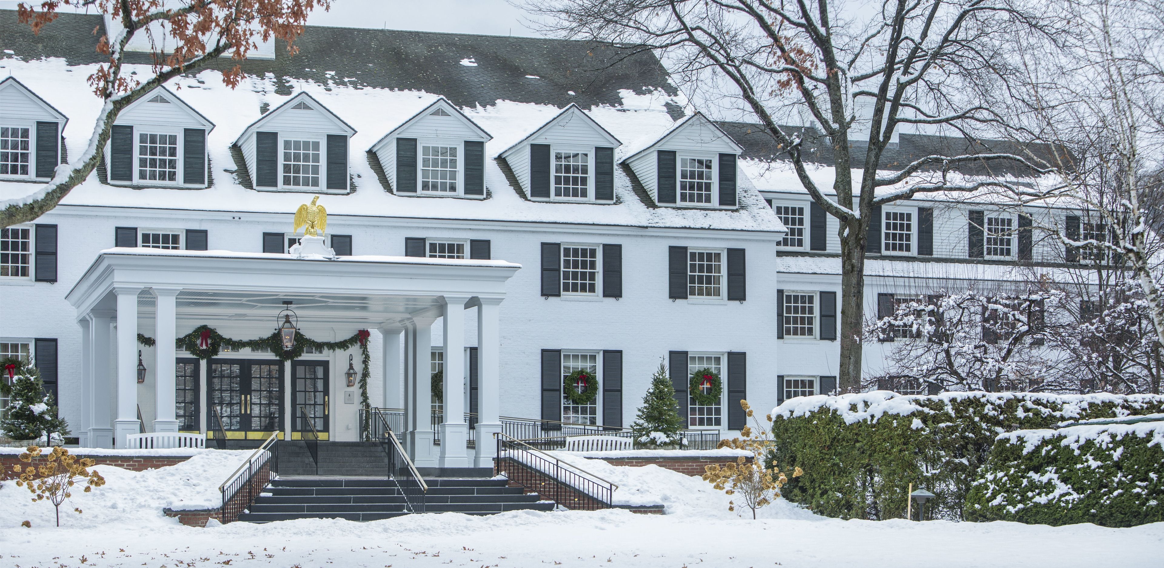 A large, white, multi-story building with a covered front porch and steps leading to the entrance.