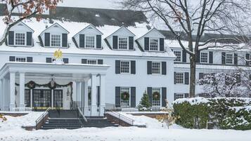 A large, white, multi-story building with a covered front porch and steps leading to the entrance.