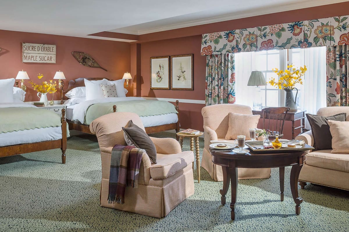 A hotel room with a bed, two armchairs, a coffee table, and a window with curtains.