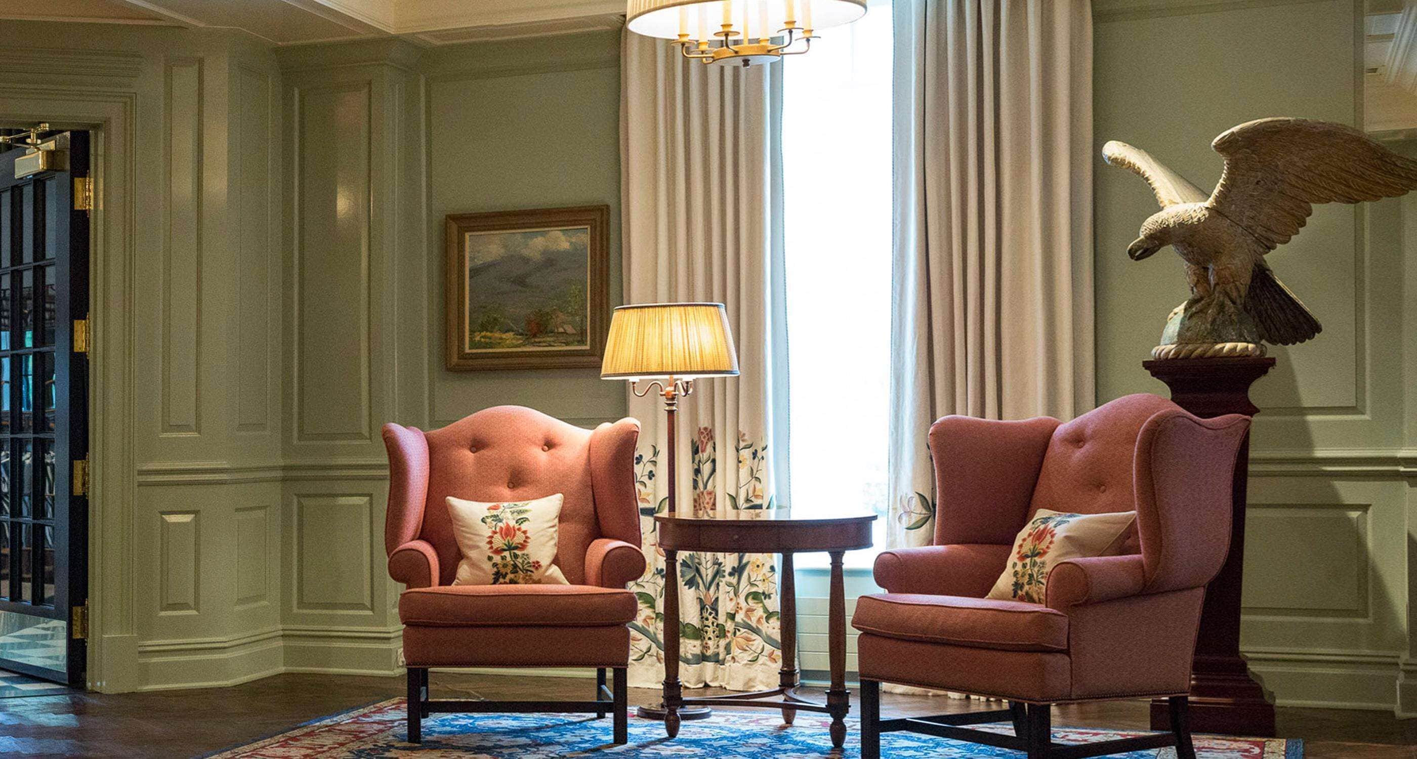 A room with two armchairs, a lamp, a table, and a decorative eagle statue.