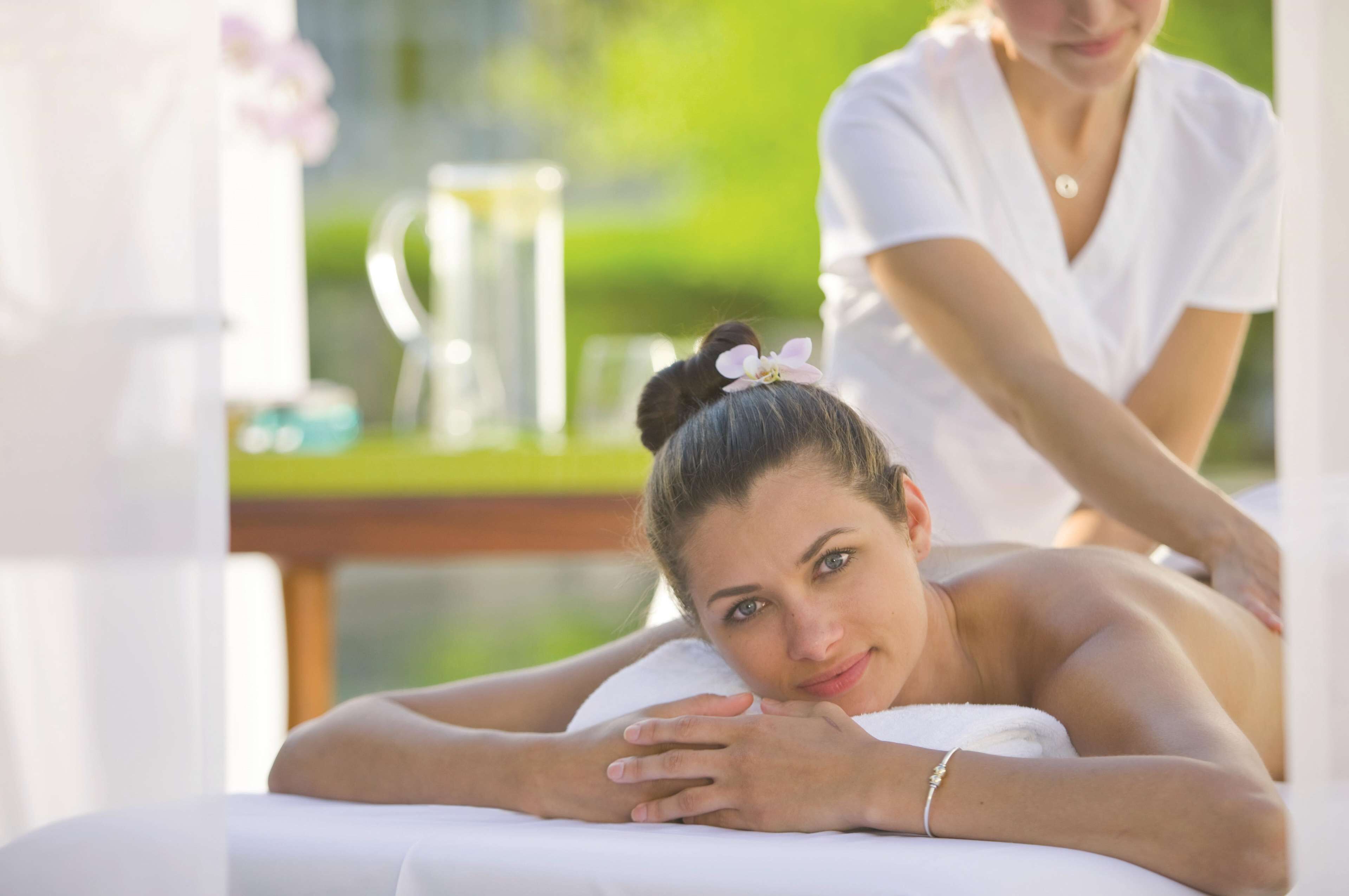 A spa setting with a massage table and a person receiving a massage.