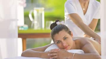 A spa setting with a massage table and a person receiving a massage.
