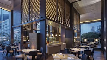 Ein modernes Restaurant mit hohen Decken, großen Fenstern und einer zentralen Bar.
