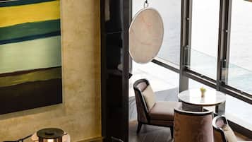 Een moderne eetruimte met een tafel met een geometrisch patroon, gestoffeerde stoelen en een hangende lamp.