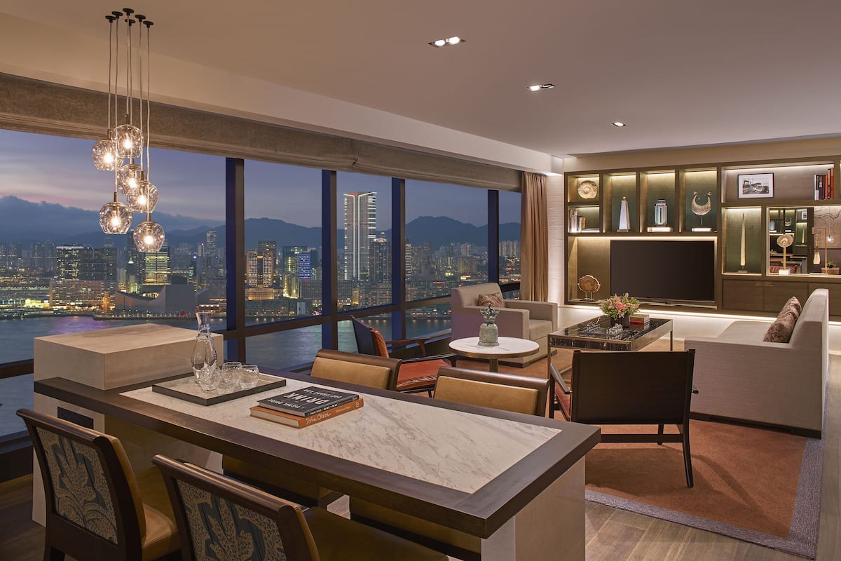A modern living room with a city view, a dining area with a marble table, and a cozy seating area.