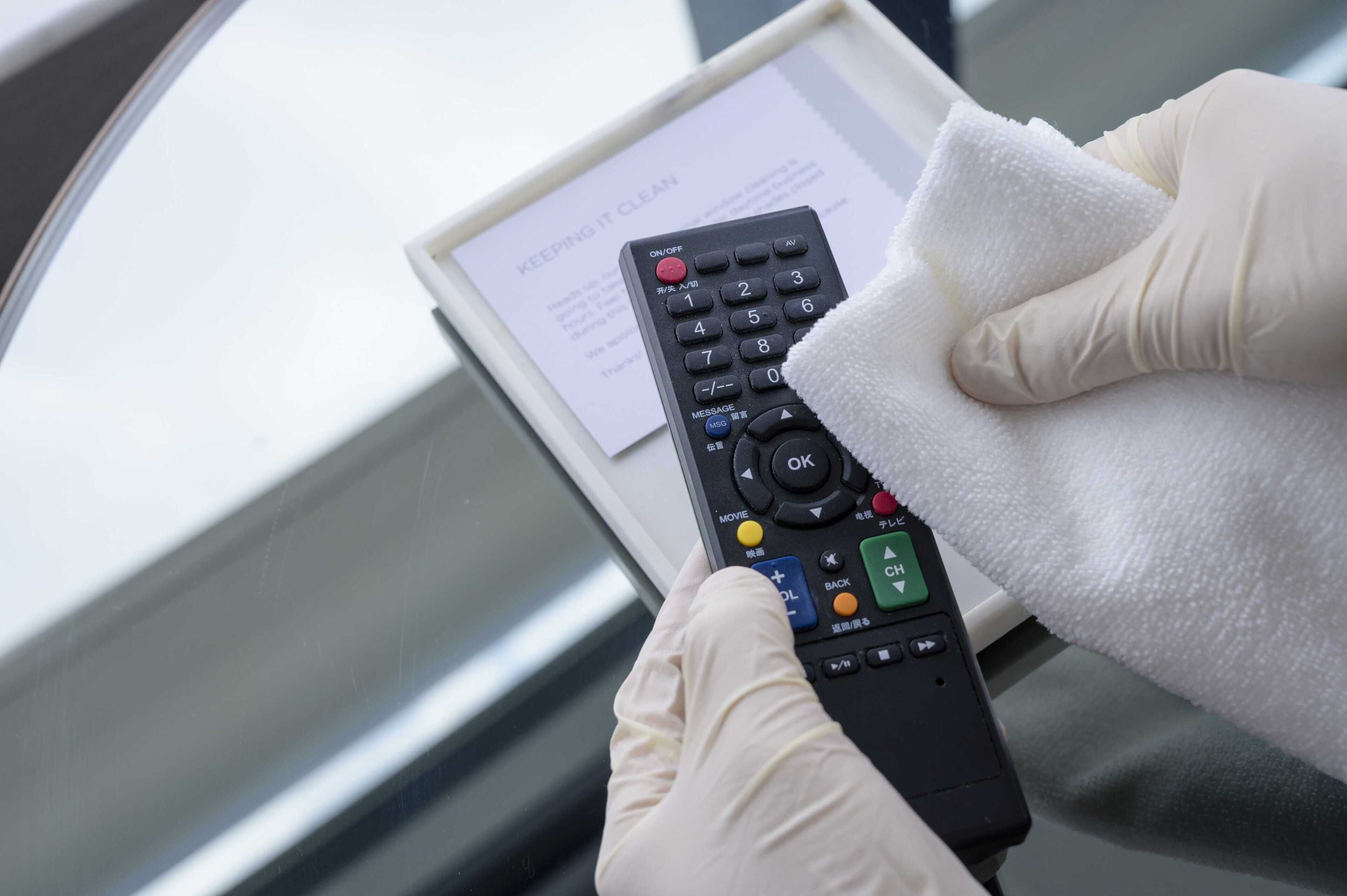 A person holding a remote control with a message about keeping it clean.