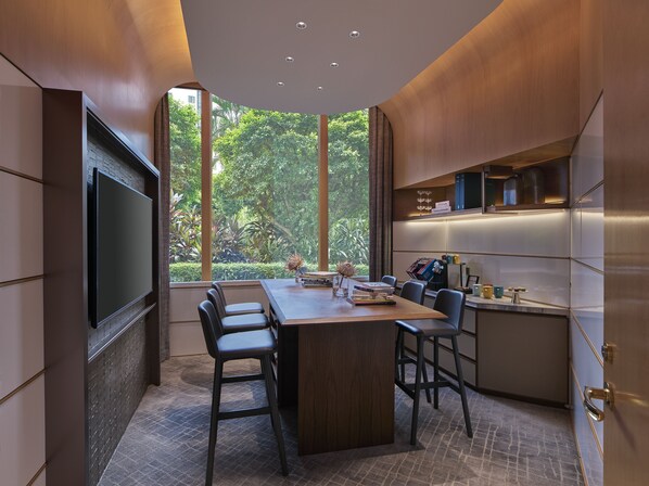 A modern dining area with a large table, chairs, and a TV mounted on the wall.