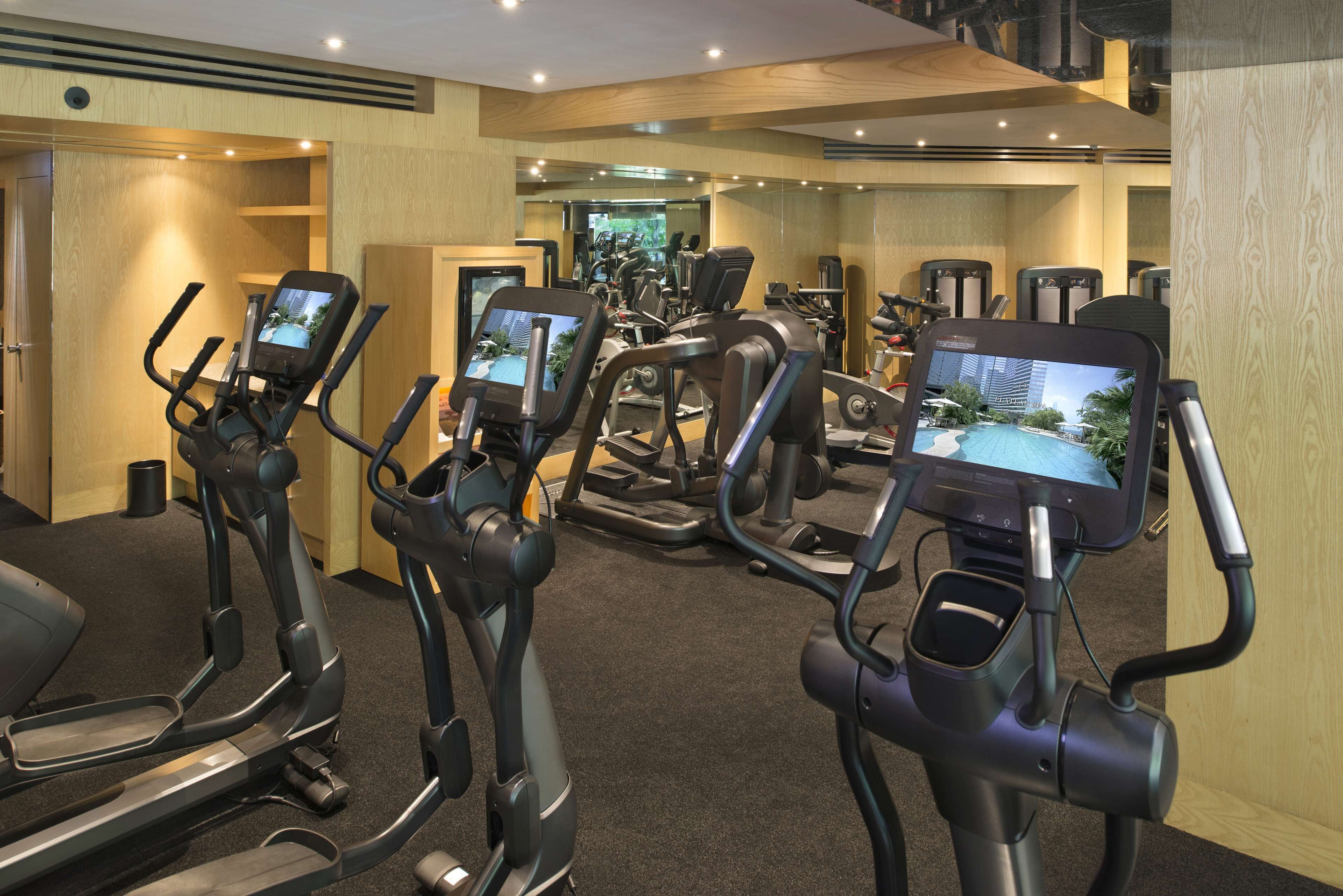 Une salle de sport dotée de plusieurs tapis de course, chacun étant équipé d’un écran numérique.