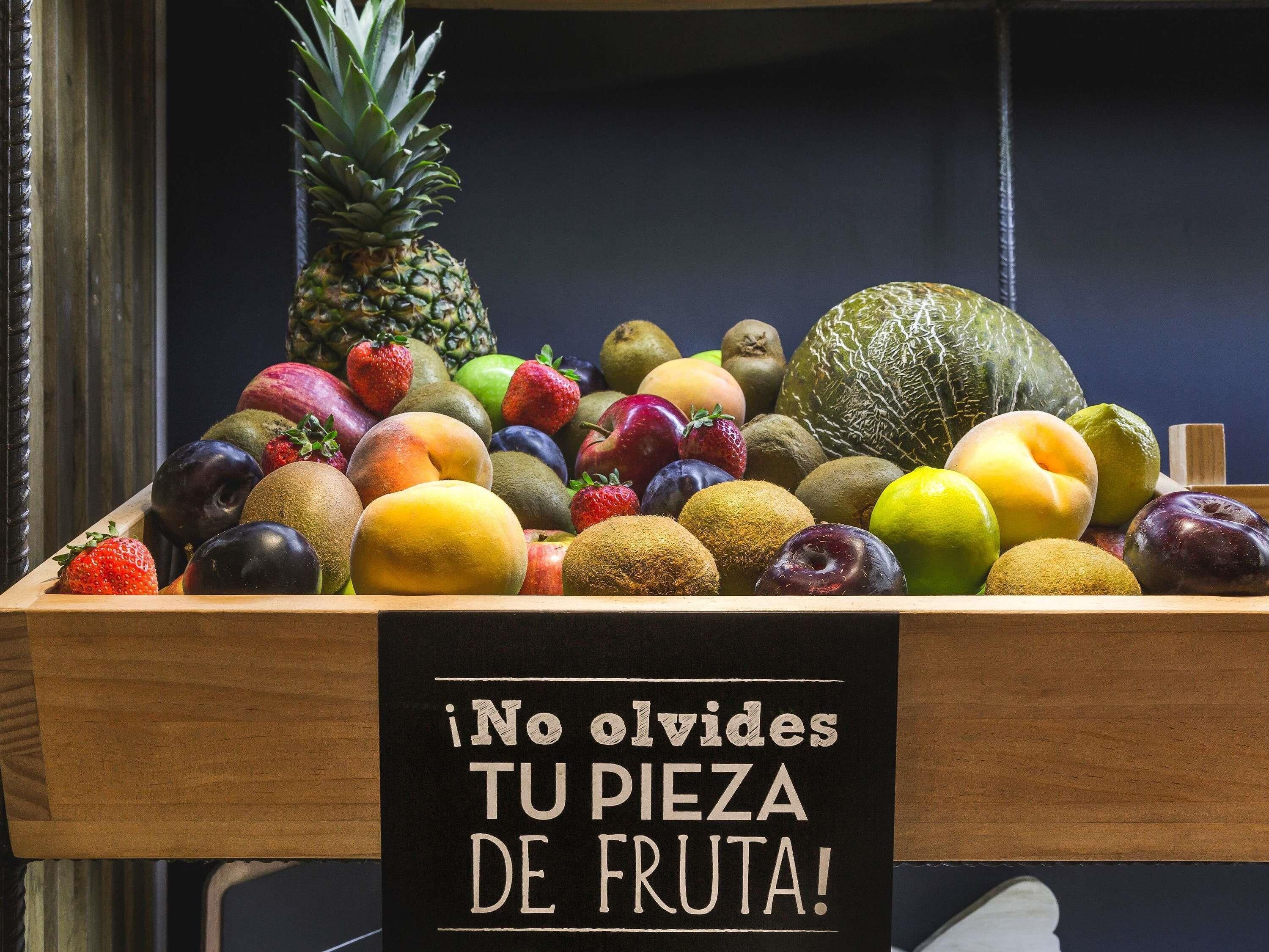 Un présentoir en bois où sont exposés des fruits, avec une pancarte en espagnol.