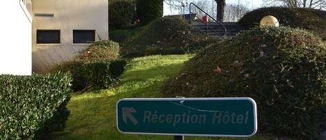 Señal de recepción de hotel con una flecha apuntando a la izquierda.