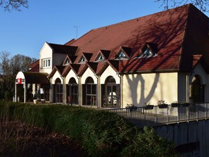 A building with a red roof, multiple arched windows, and a covered entrance.