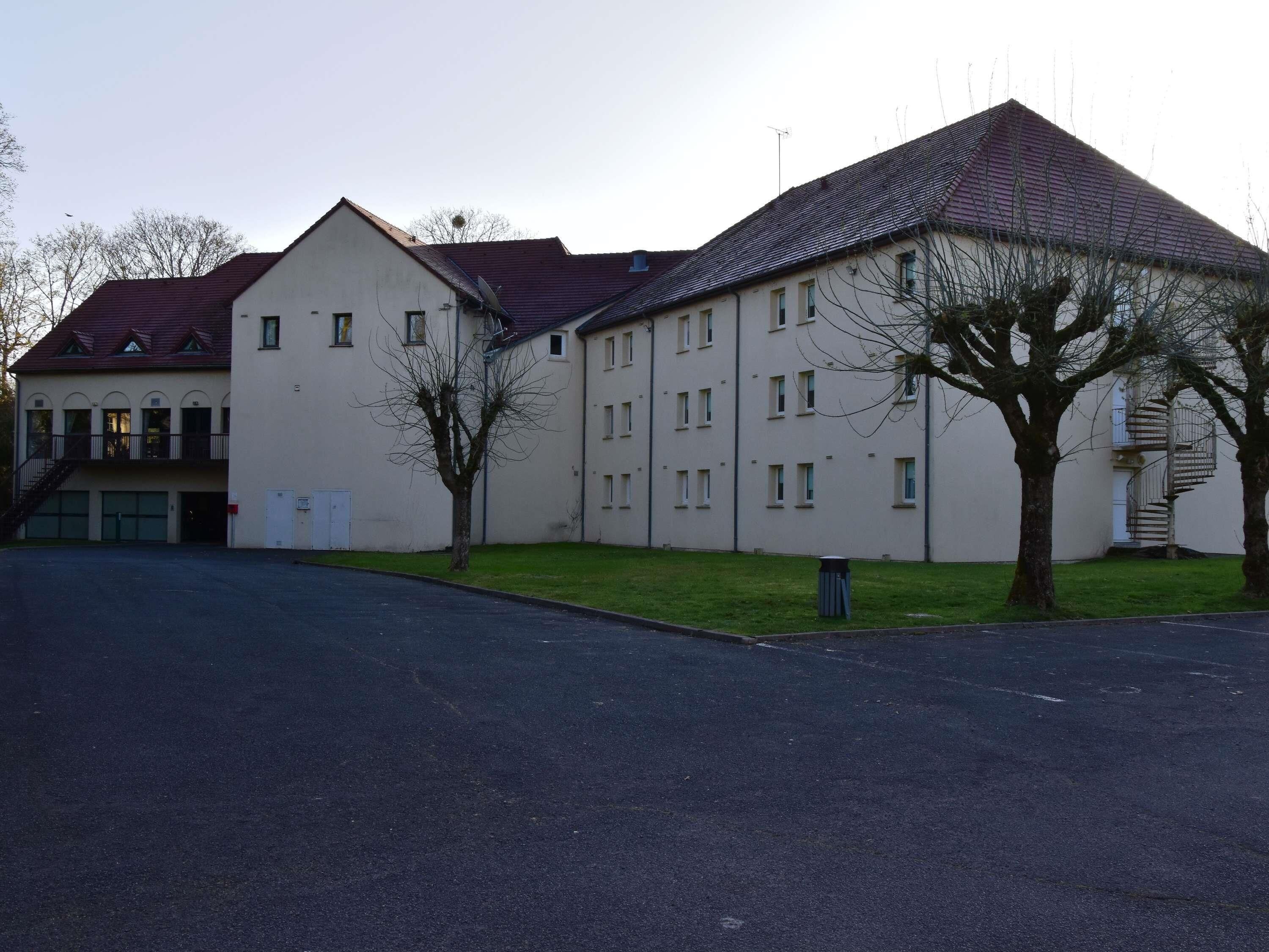 Ein Gebäude mit flachem Dach, zahlreichen Fenstern und einer Treppe, die zu einem Balkon führt.