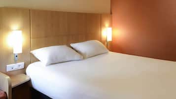 A hotel room with a bed, two bedside lamps, a nightstand, and a power outlet.