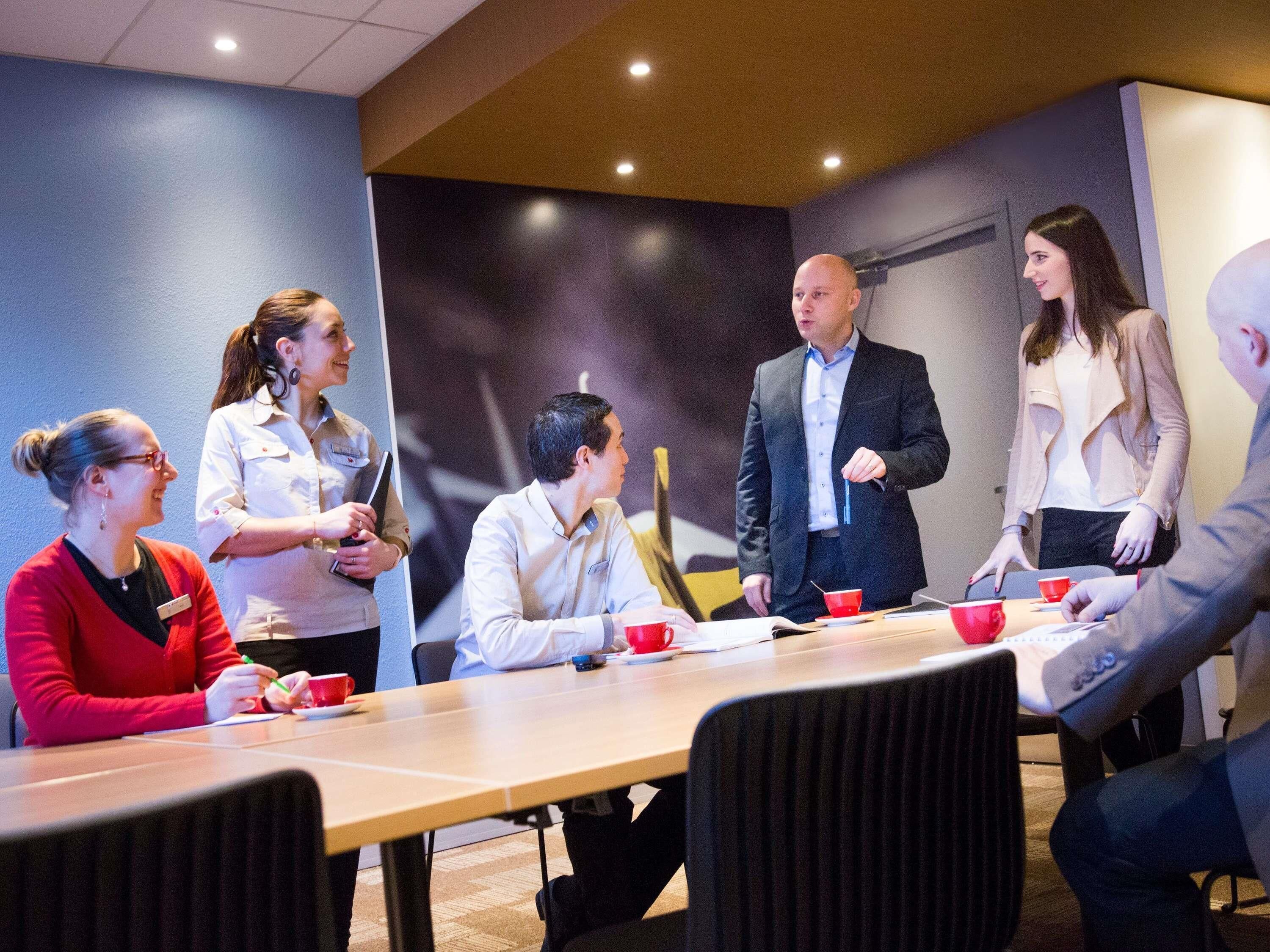 A conference room with a long table, chairs, and a group of people engaged in a meeting.