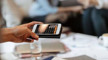A person holding a smartphone with a numeric keypad.