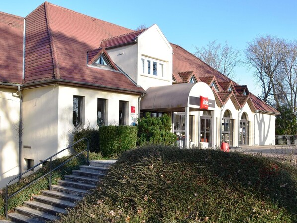 A building with a red roof, a white facade, and a staircase leading to the entrance.
