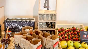 Un bufé de desayuno con alimentos identificados, un letrero con ilustración de un chef y una exhibición de frutas frescas.