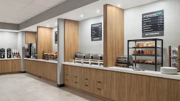 Una barra de desayuno moderna con detalles de madera, un panel con la carta y diversos alimentos expuestos.