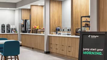 A modern breakfast area with wooden cabinets, a coffee station, and a sign promoting a hearty breakfast.