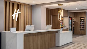 A reception area with a marble counter, wooden paneling, and a large illuminated 'H' sign.