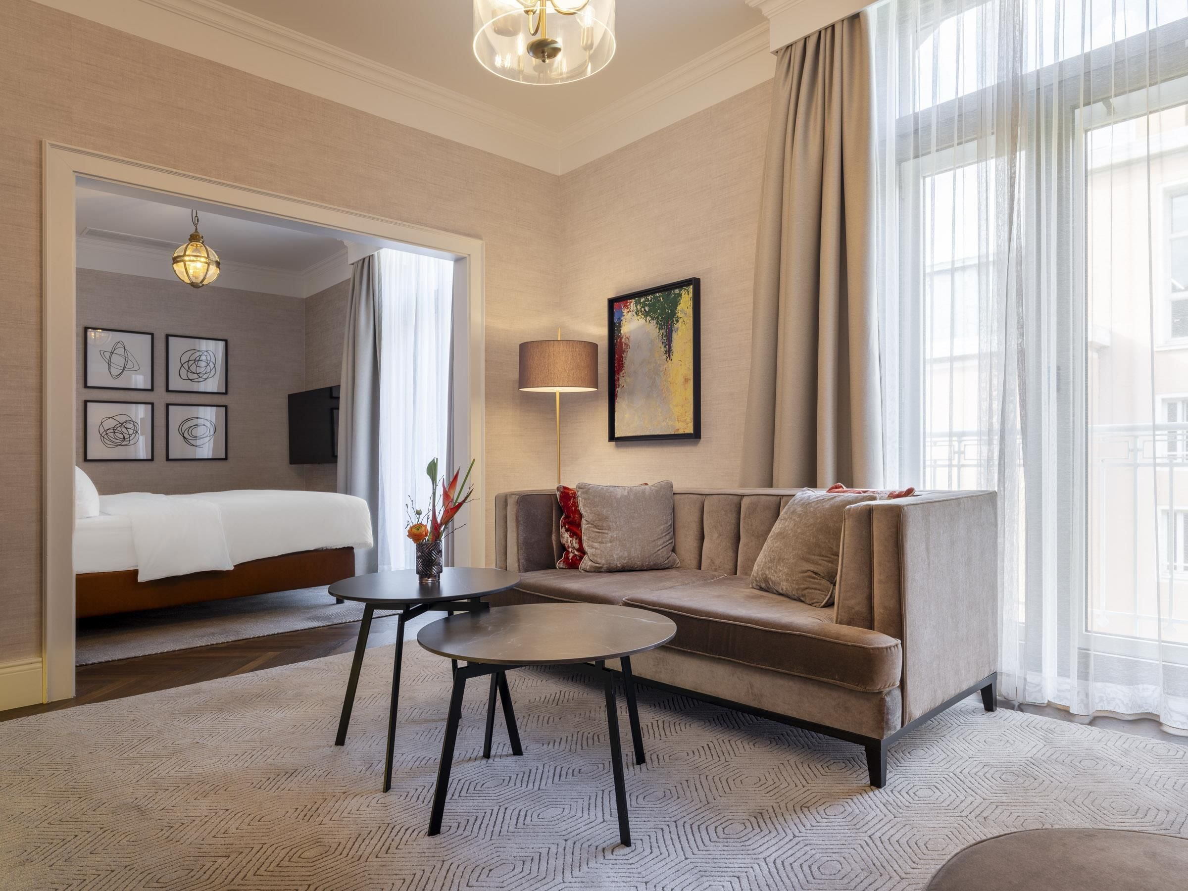 A hotel room with a bed, a sofa, a coffee table, and a painting on the wall.