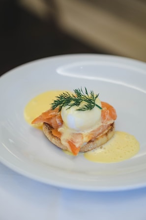 Une assiette contenant un plat composé de saumon fumé, d’œuf poché et de sauce hollandaise.