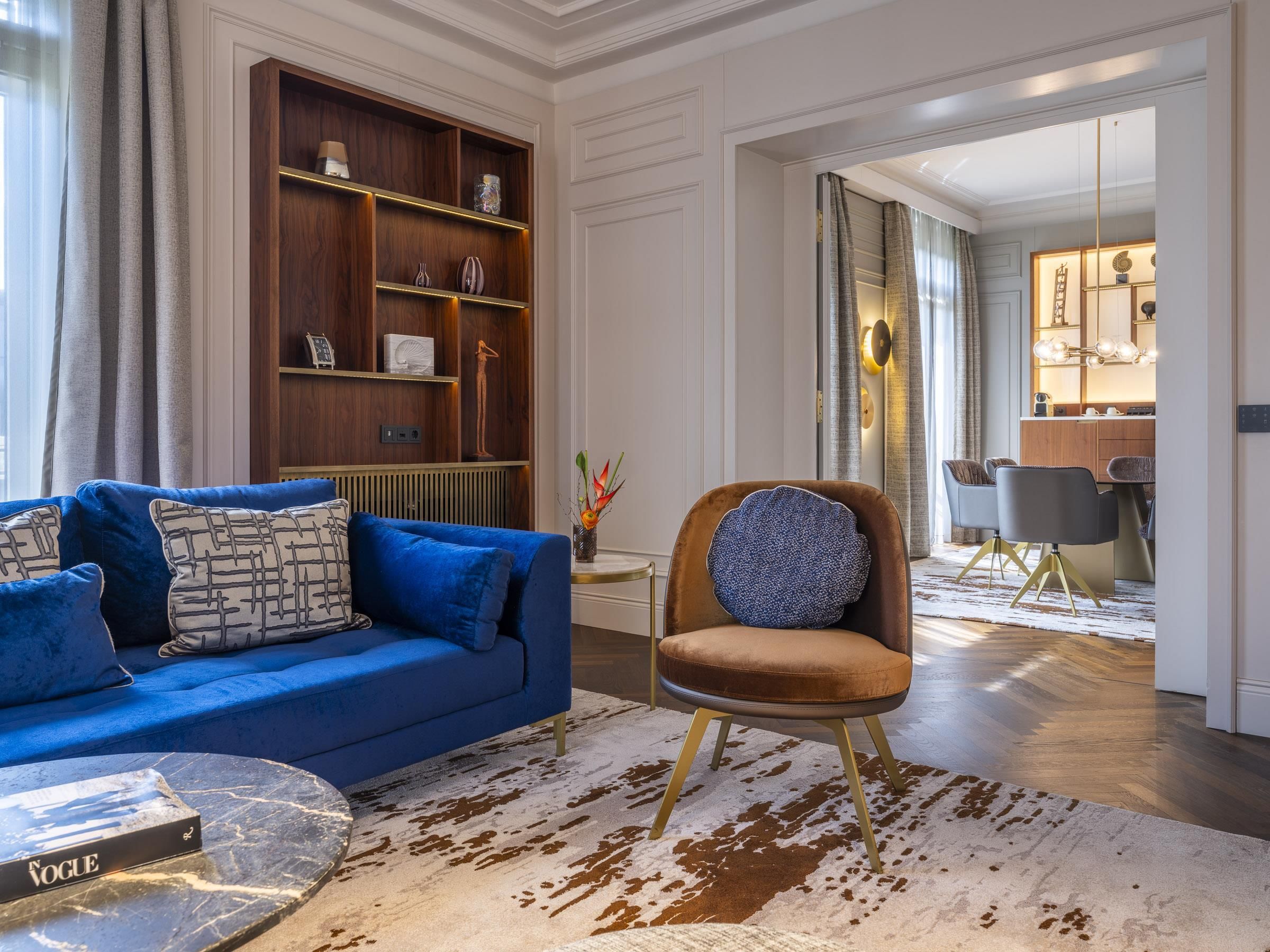 A modern living room with a blue sofa, a brown armchair, and a coffee table.