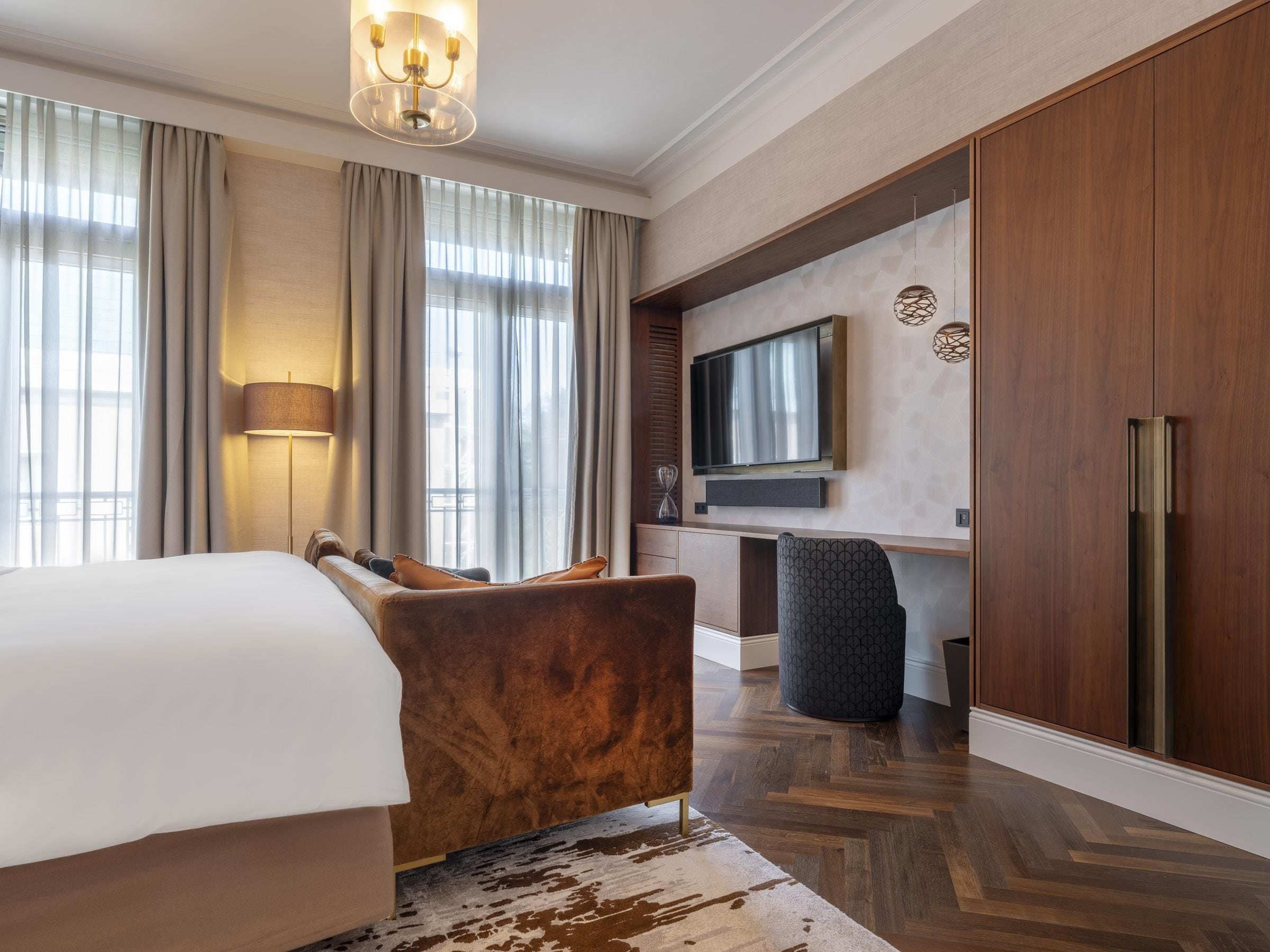 Habitación de hotel con cama, sofá, televisor y armario.