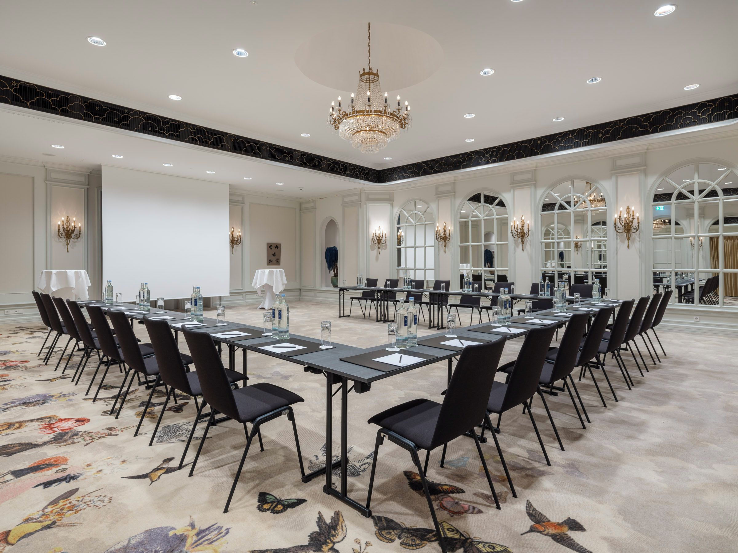 A large conference room with long tables, chairs, and a chandelier.